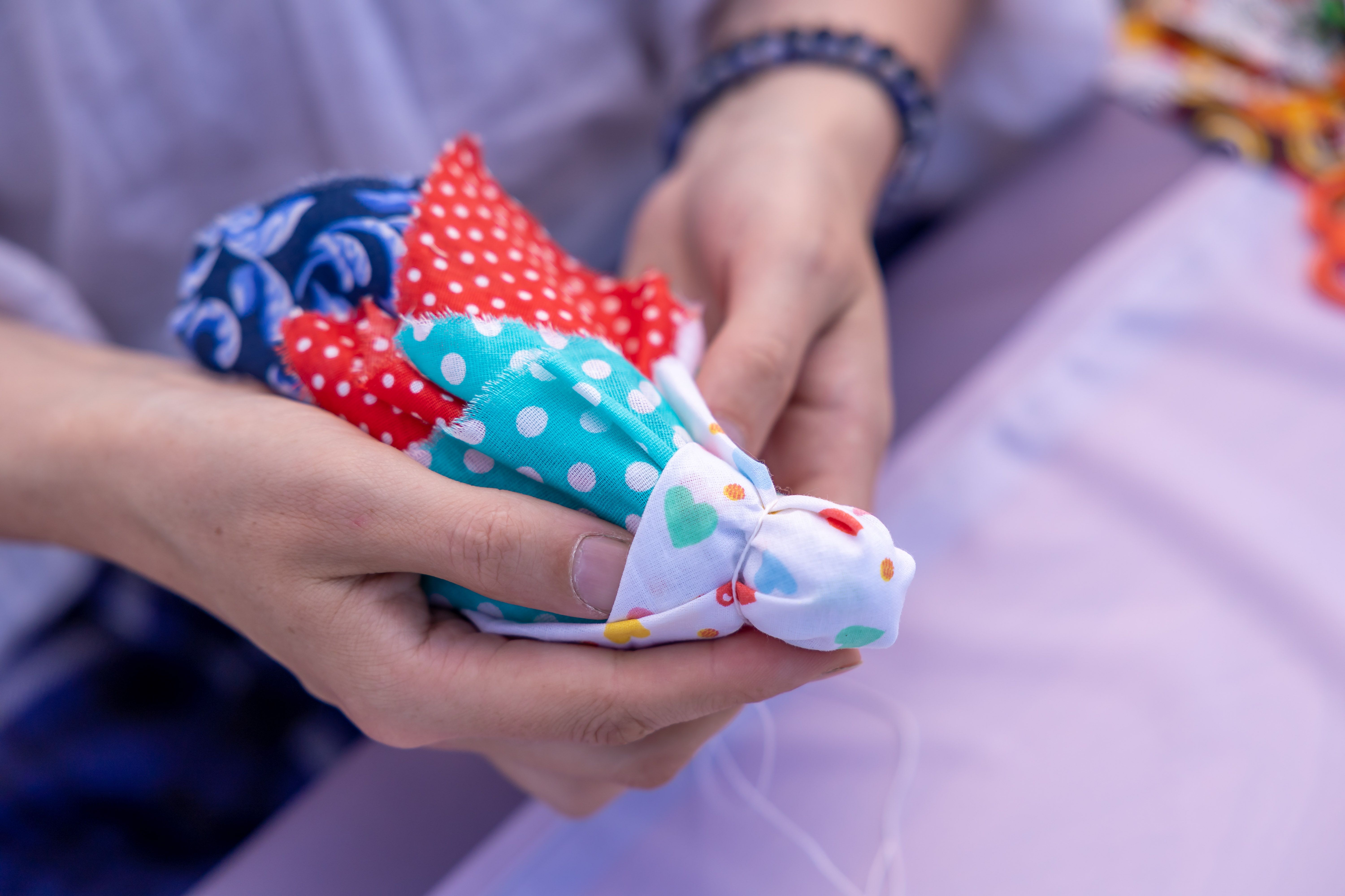 Close-up of hands holding vibrant, patterned fabric pieces for crafting. — Maynard Longarm Quilting