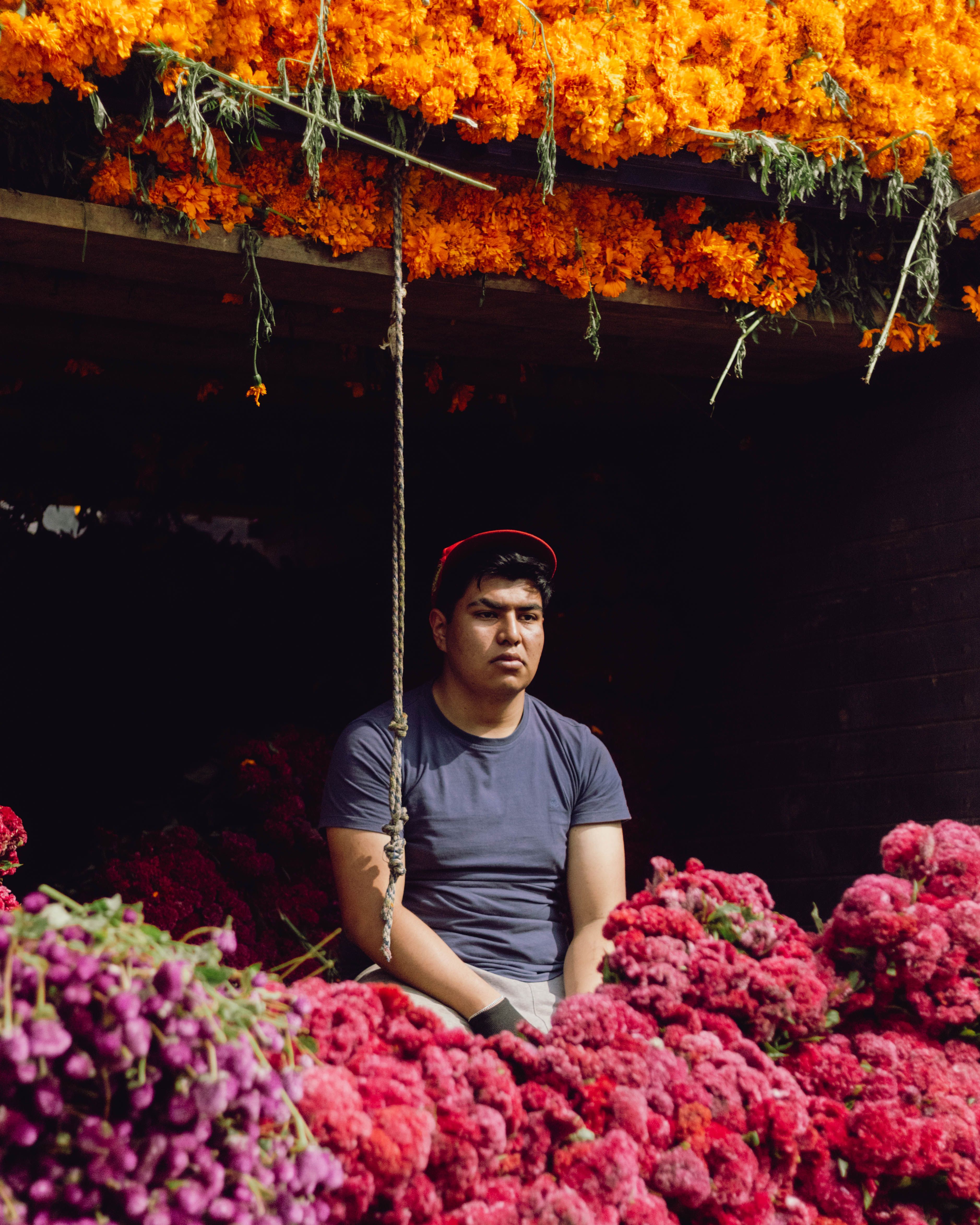 A vendor surrounded by vibrant marigold flowers at a market in Mexico City.
