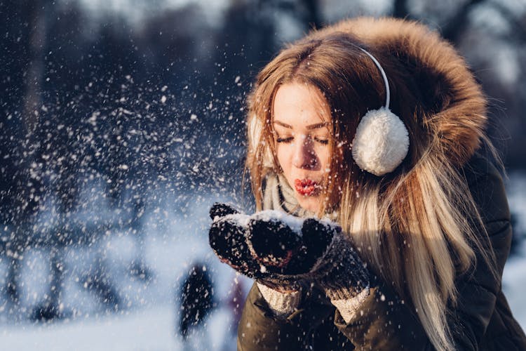 Woman Blowing Snow From Hand