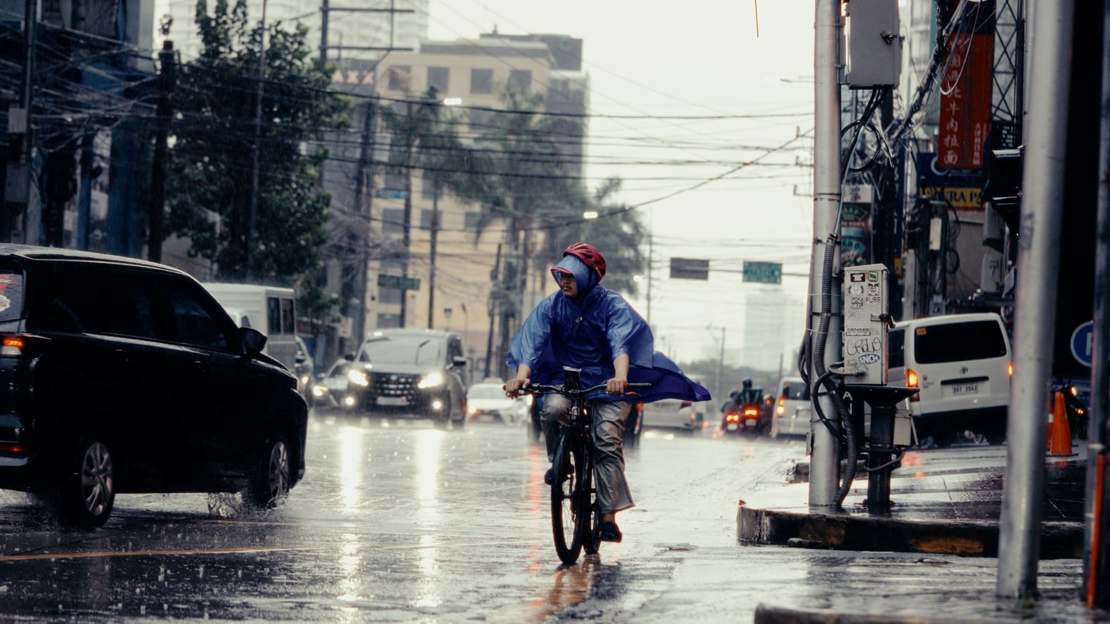 Commuter cyclist wearing rain protection on a wet city street