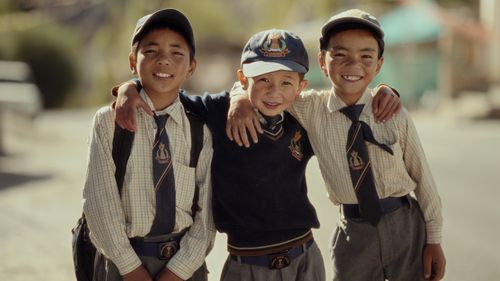 Free Three schoolboys wearing uniforms smiling on a sunny day, representing friendship and youth. Stock Photo