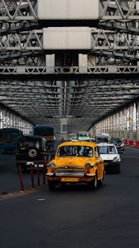 Yellow taxi driving on Howrah Bridge in Kolkata, capturing morning city life and iconic Indian architecture.