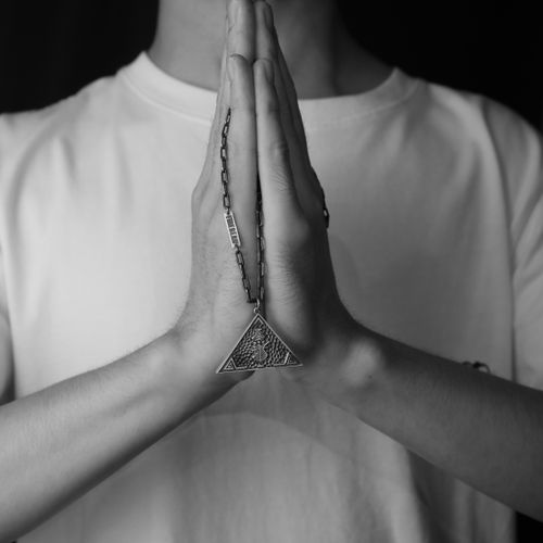 Free Black and white image of clasped hands in prayer with a triangle pendant. Stock Photo