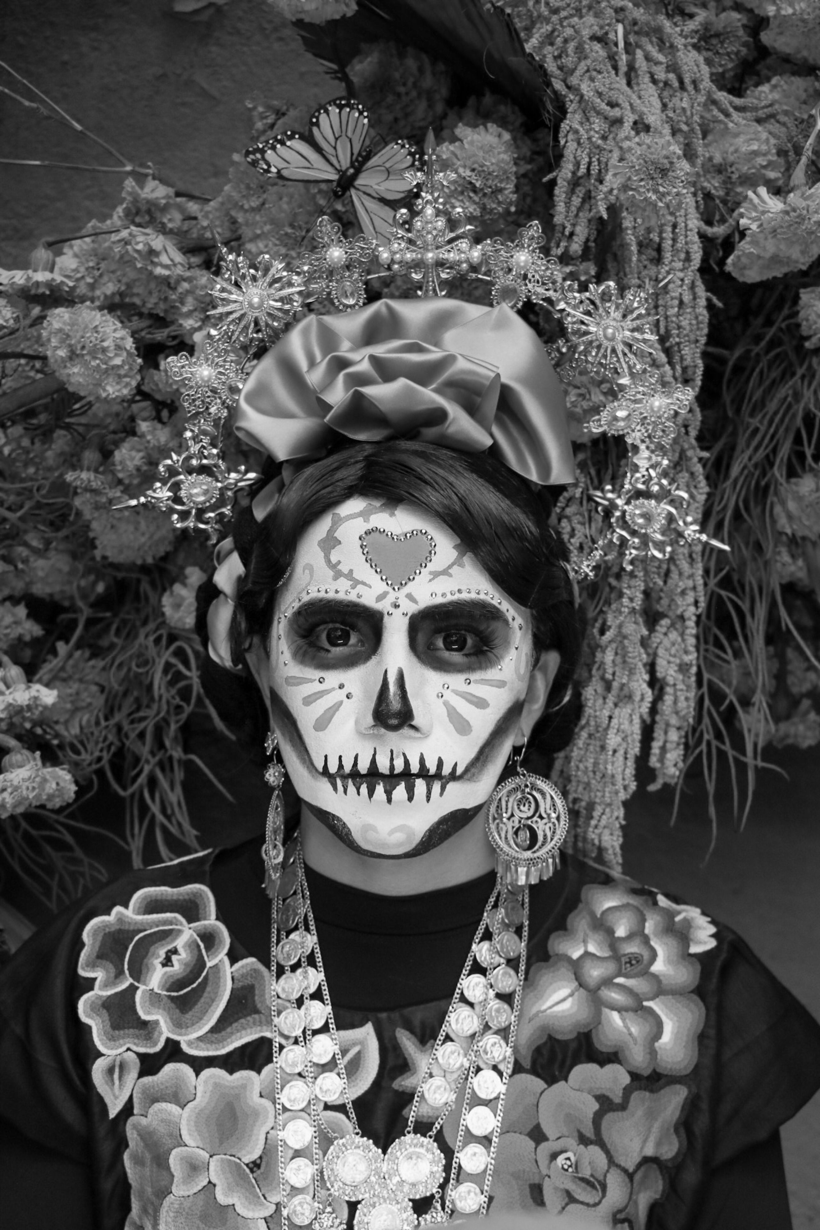 A person wearing Day of the Dead makeup with floral decorations and traditional attire.