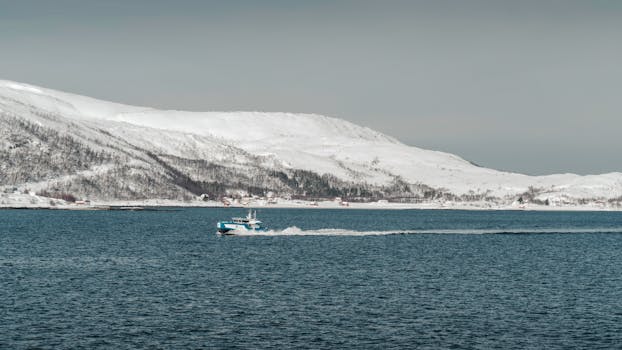 Peaceful winter scene with a boat on a snowy Norwegian fjord.