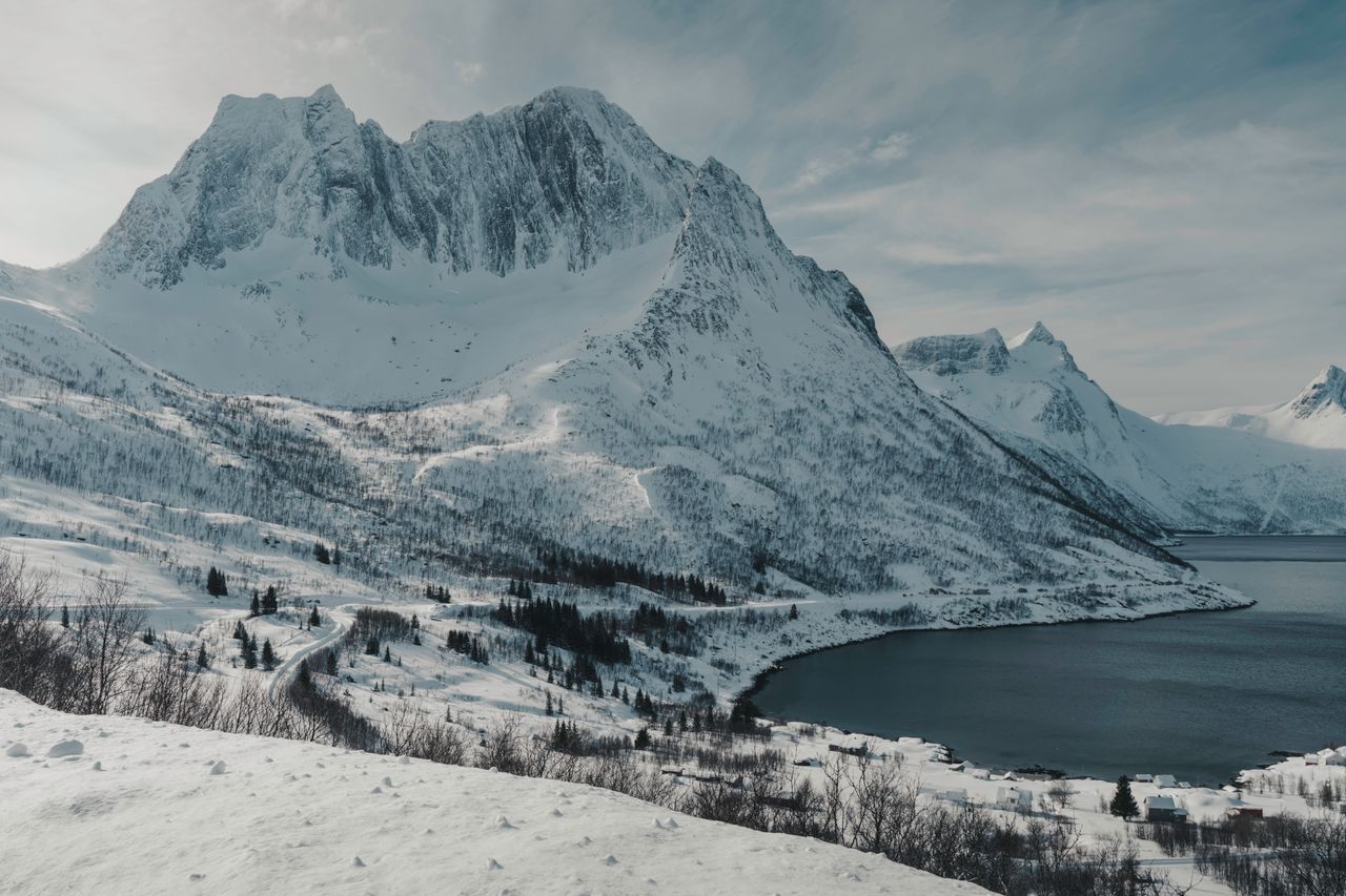 snowy mountains over a serene fjord in the norwegian arctic circle con