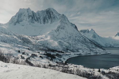 Free Snowy mountains over a serene fjord in the Norwegian Arctic Circle, conveying winter tranquility. Stock Photo