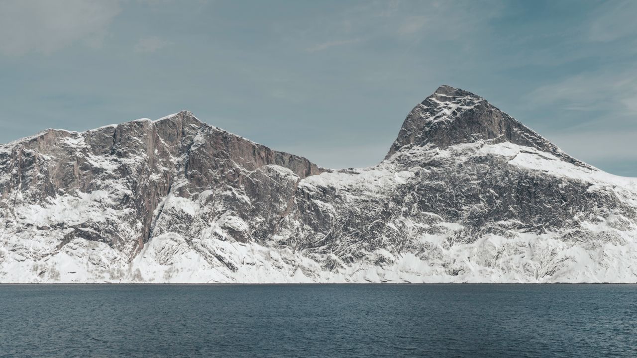 majestic snow covered mountains rising over the calm sea in an arctic
