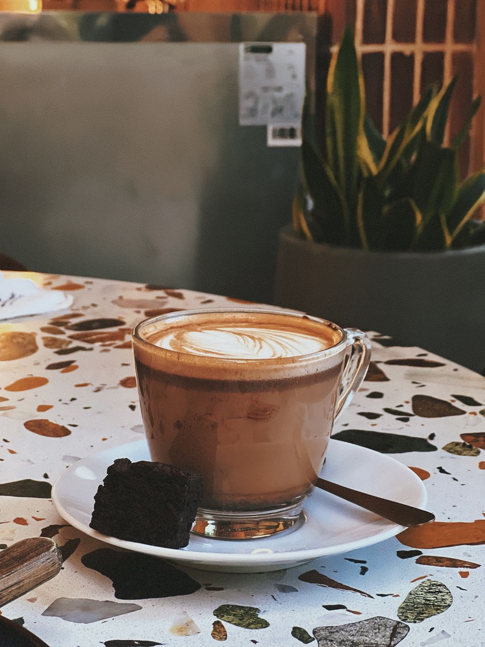 A warm cup of coffee with artistic foam pattern on a cafe table, perfect for afternoon relaxation.
