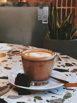 A warm cup of coffee with artistic foam pattern on a cafe table, perfect for afternoon relaxation.