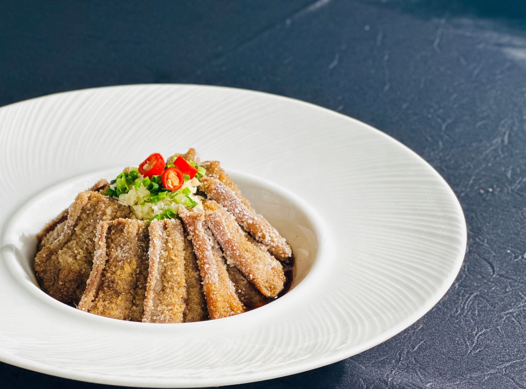 Delicious gourmet dish featuring crispy Chinese eggplant with chili and garlic garnish.