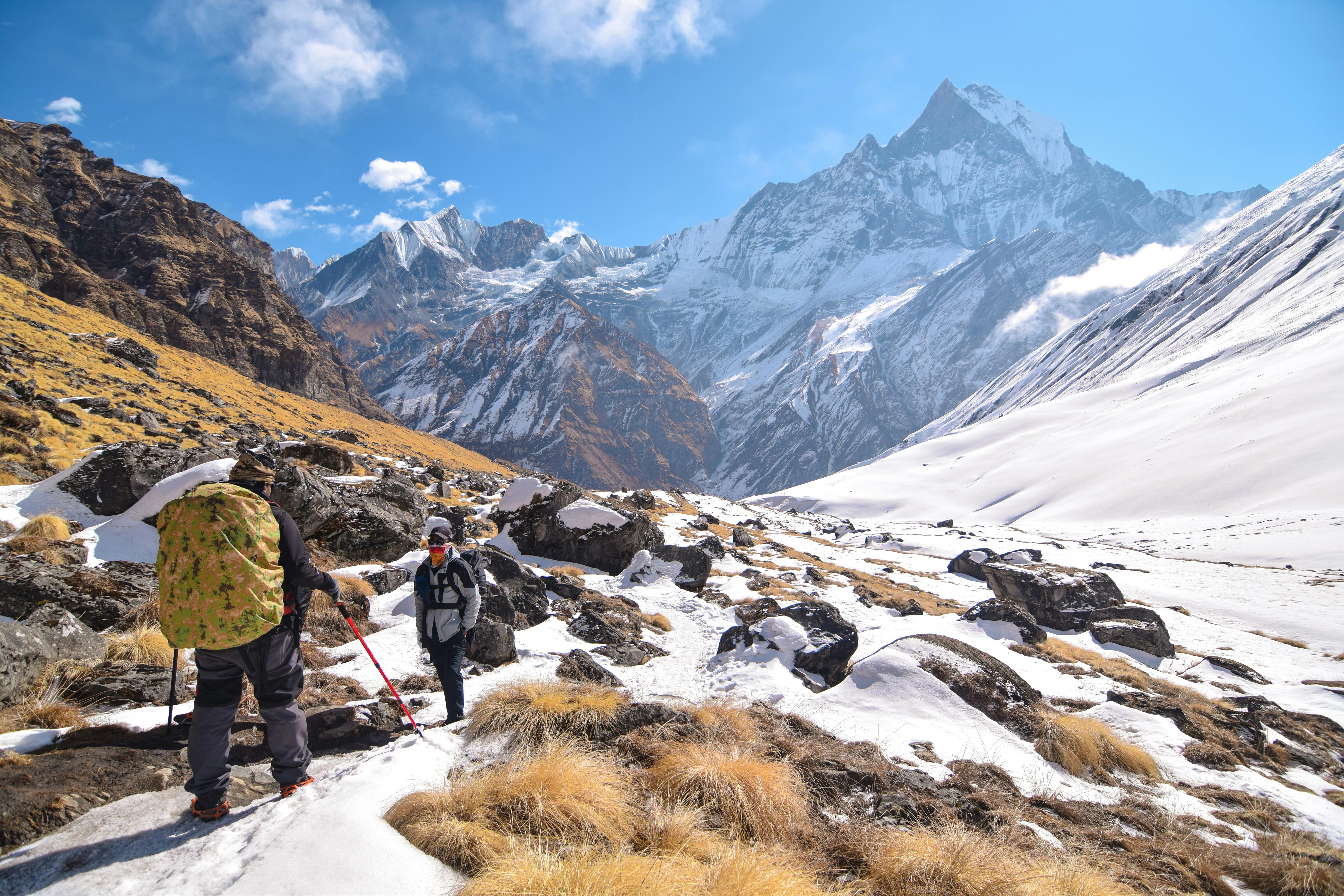 Prescription Goggle Inserts - Two hikers trek through the snow-covered mountains of Khangsar, Nepal, under a vivid blue sky.