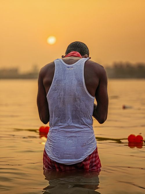 Free Person performing spiritual ritual in river during sunset, Kolkata, India. Stock Photo
