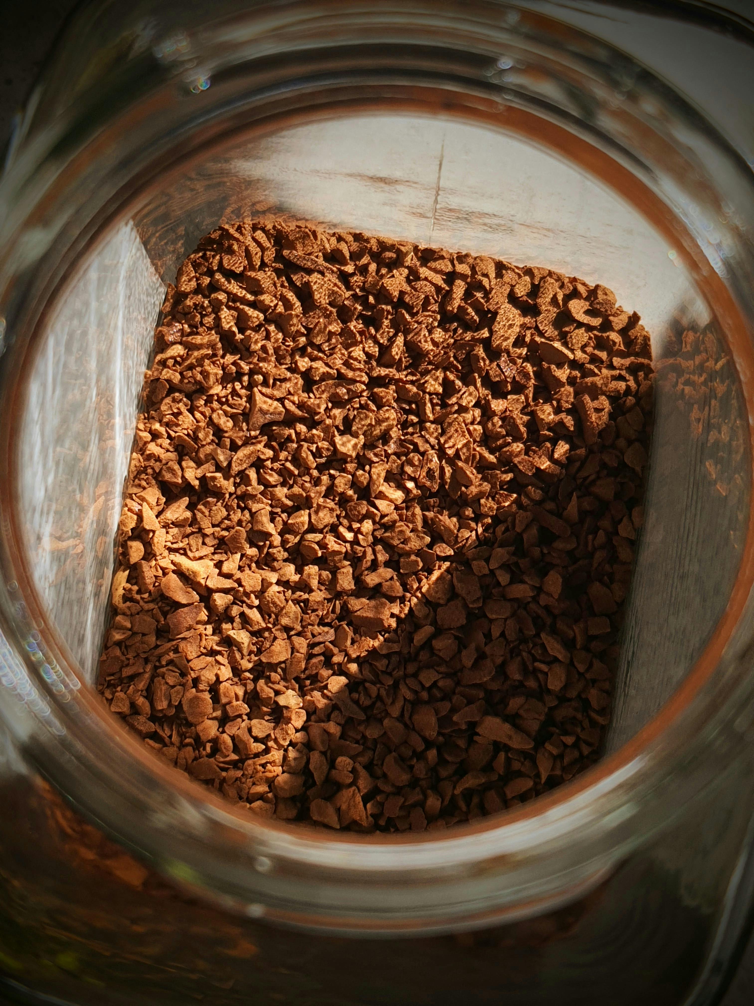 Sunlit instant coffee granules inside a glass jar