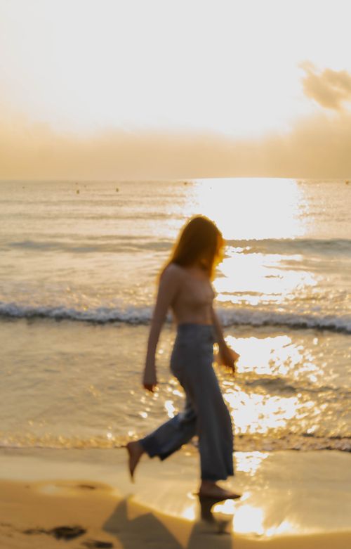 Free Silhouette of a woman strolling along a sunlit Calp beach at sunset, capturing tranquility. Stock Photo