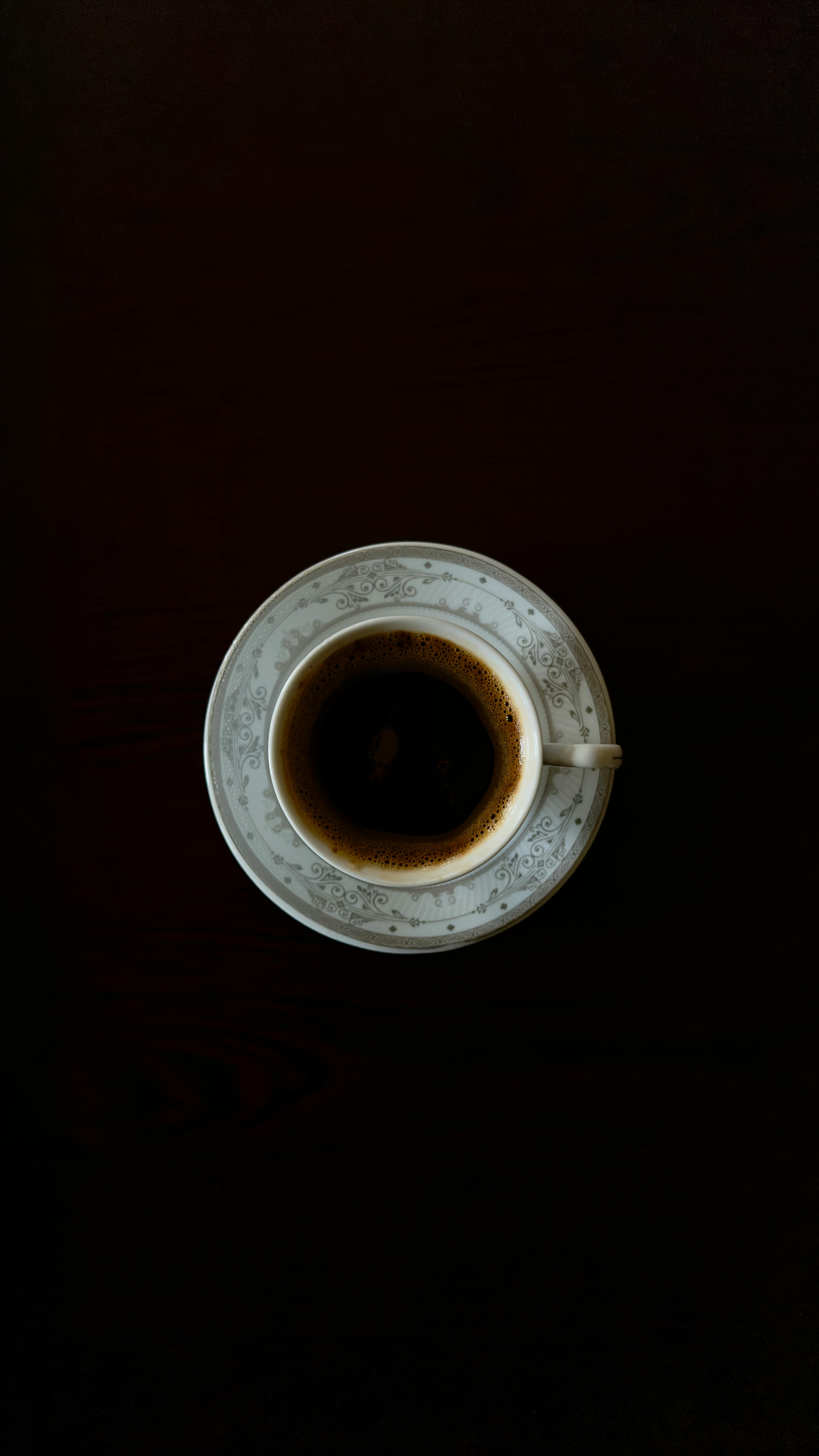 Kostenlos Draufsicht einer verzierten Kaffeetasse auf dunkler Oberfläche, perfekt für Food-Blogs. Stock-Foto