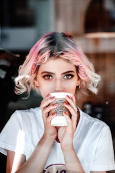 一位年轻女子，粉红色头发，在咖啡馆里拿着杯子的肖像