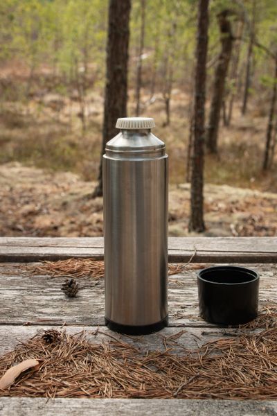 Customer photo: the flask on a weathered picnic table in the woods — Edita Brus on Pexels