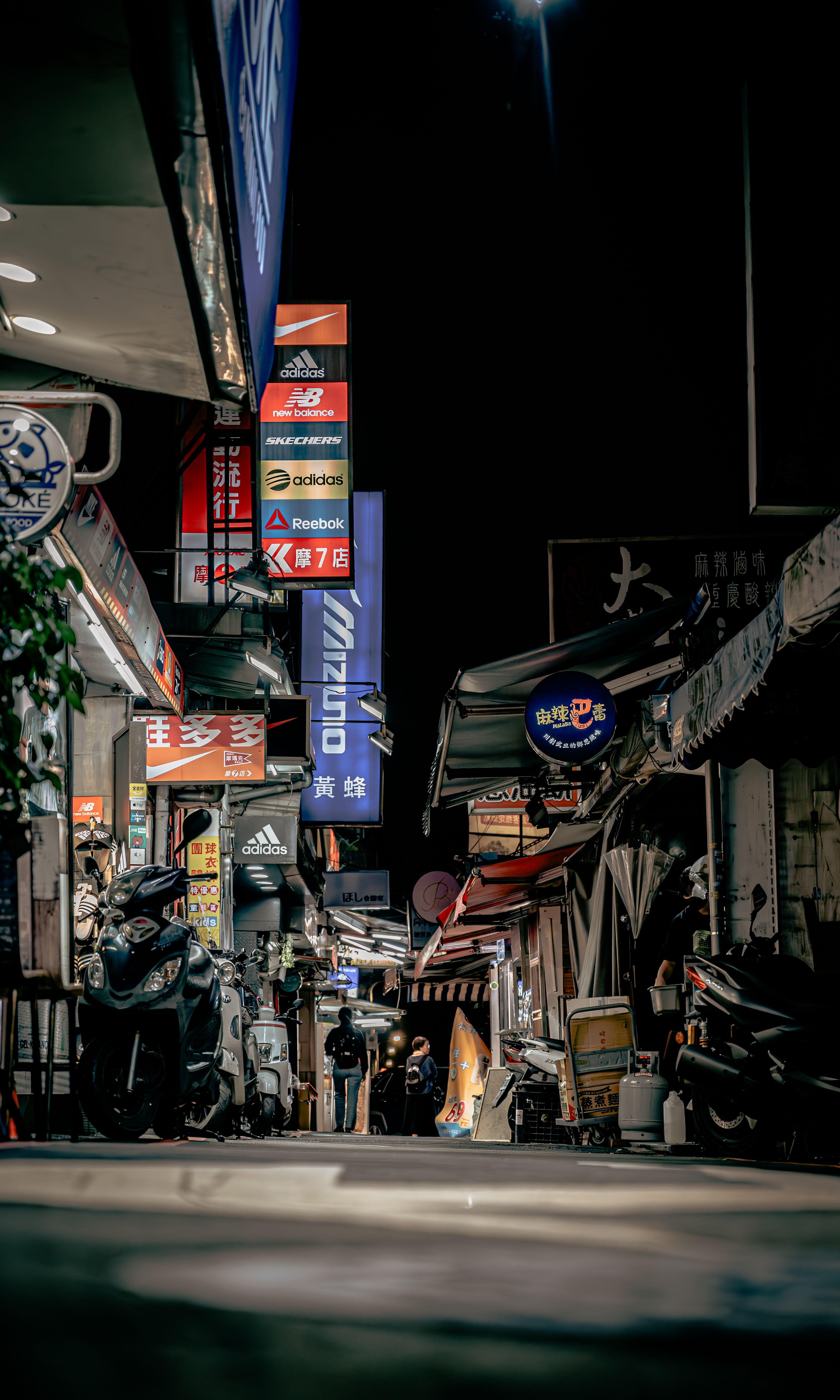 Explore the lively night scene with vibrant neon signs in a bustling Taipei street market.