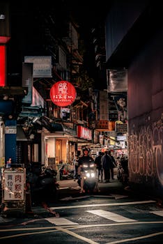 Nighttime bustling street scene in Taipei's vibrant market with neon lights and people exploring.