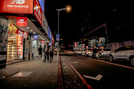Vibrant nighttime street in Taipei featuring shops and traffic.