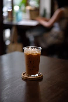 A cold iced coffee on a wooden table in a cozy café, perfect for a relaxing day.
