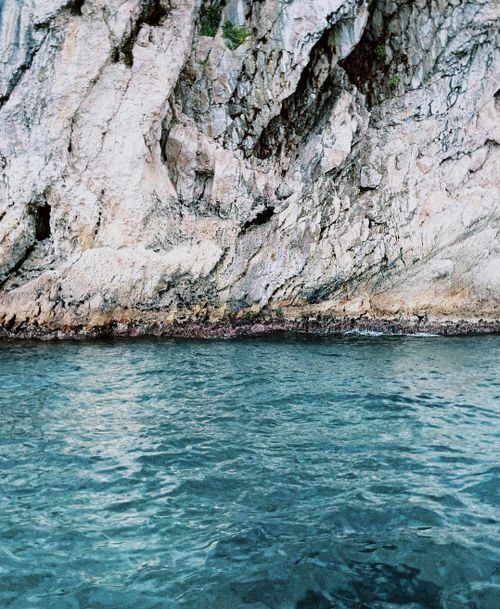 Free A stunning view of a rocky cliff meeting turquoise waters, perfect for nature and travel imagery. Stock Photo