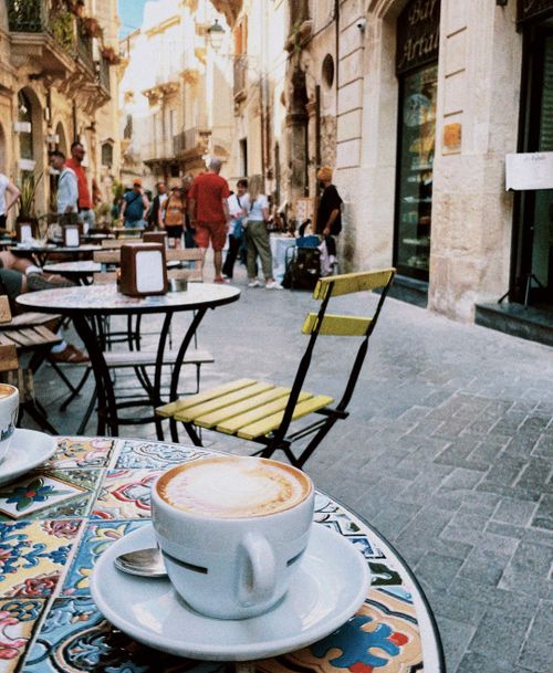 Free Cozy outdoor cafe in a Sicilian street with cappuccino and vibrant atmosphere. Stock Photo