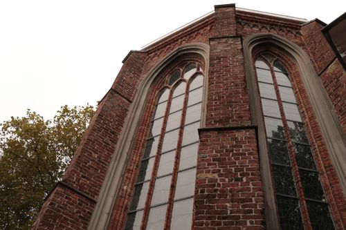 Free Low-angle shot of a Gothic church facade in Leeuwarden, showcasing its intricate brickwork and large arched windows. Stock Photo