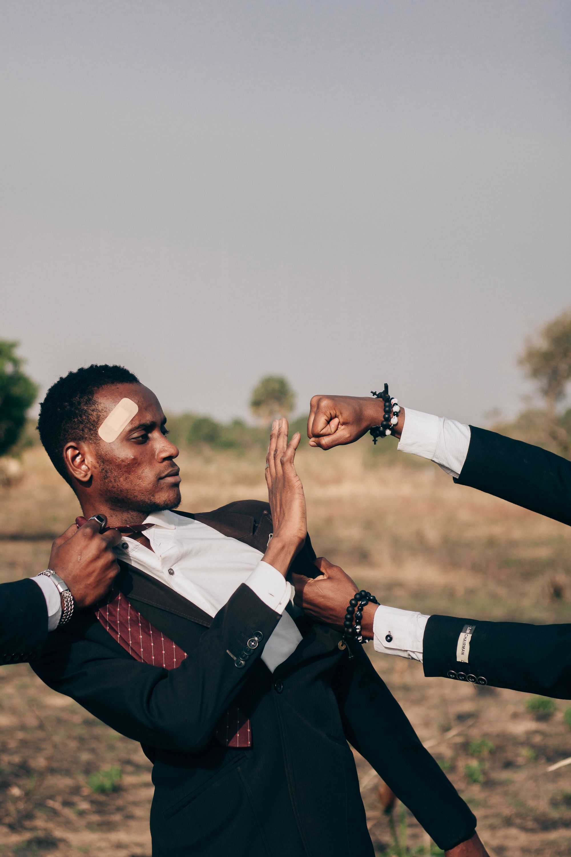 Man in Suit Defending Against Multiple Hands Outdoors · Free Stock Photo