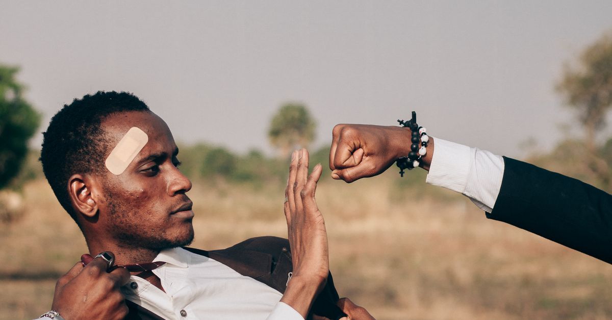 Man Defrending Man in Suit Defending Against Multiple Hands Outdoors · Free Stock Photo