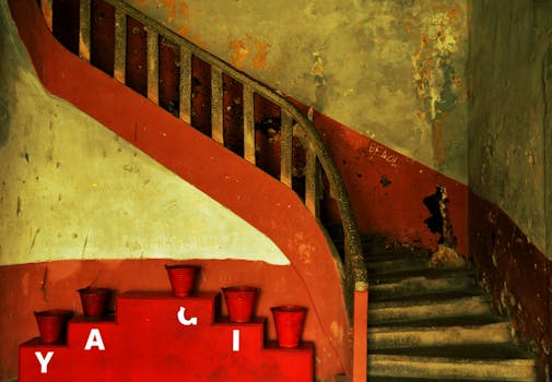 An old, rustic staircase with red decor buckets inside a vintage building, exuding a nostalgic feel.