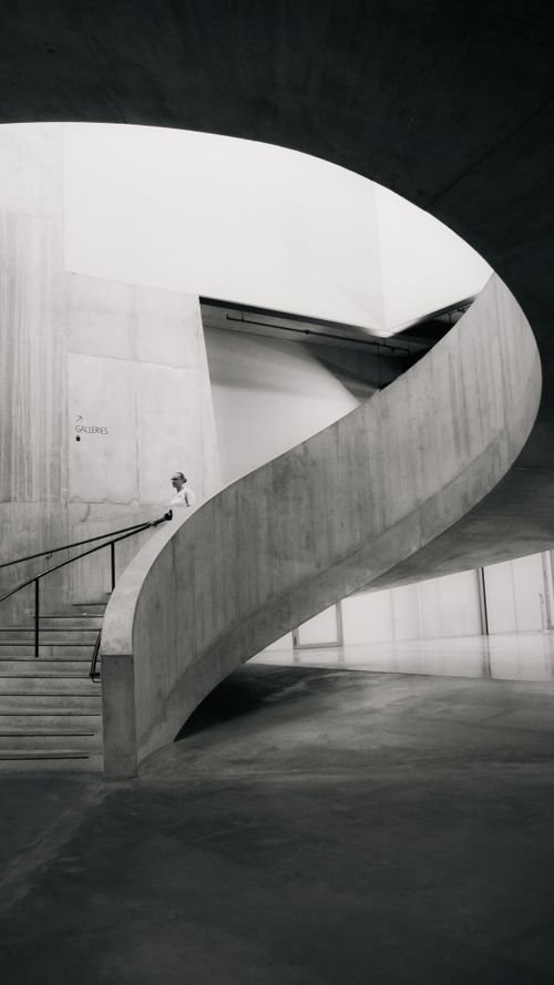 Free Monochrome image of a modern brutalist concrete spiral staircase in a gallery. Stock Photo