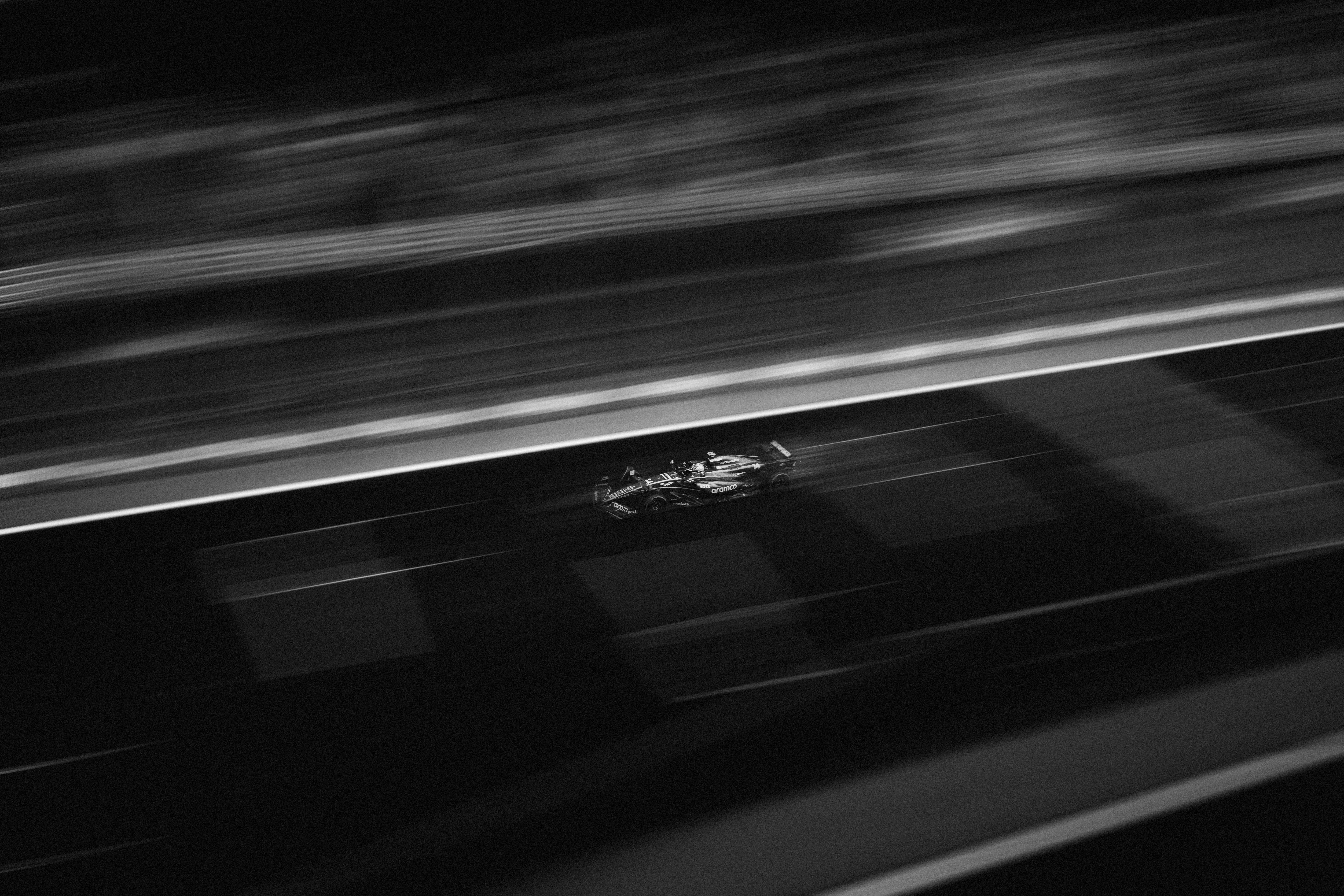 무료 야간 경주 중 트랙에서 고속으로 달리는 포뮬러 레이싱 카를 포착한 흑백 이미지입니다. 스톡 사진