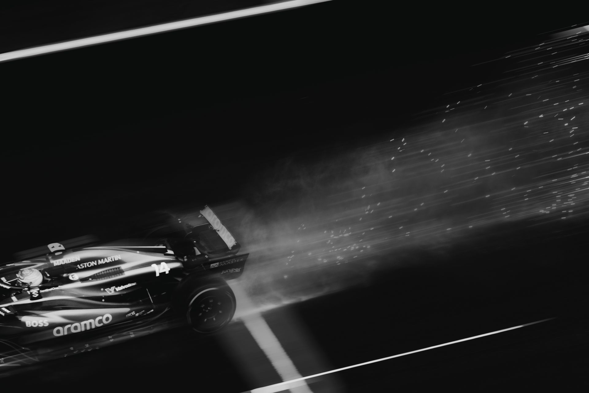 A dramatic black and white photo capturing a racing car moving at high speed, leaving a water spray trail.