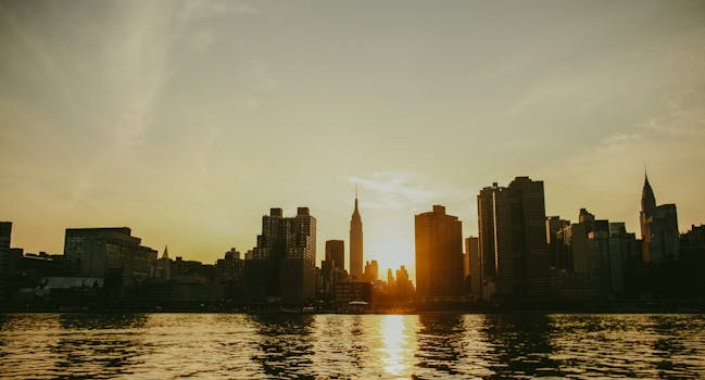 日落时分，迷人的纽约天际线倒映在水面上，展示着标志性的摩天大楼