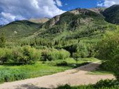 Lush green landscape with mountains under a bright blue sky in Colorado.