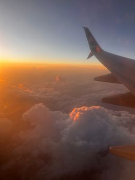 Tranquil view of an airplane wing over clouds at sunset, capturing a serene sky scene.