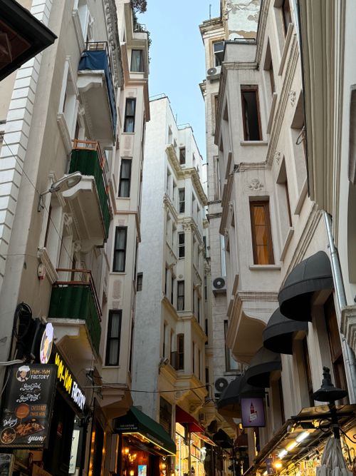 Free Narrow alleyway in a European city, lined with classic architecture, cafes, and shops. Stock Photo