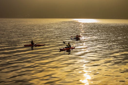 Three people enjoy a peaceful canoe trip on a lake at sunset with golden reflections.
