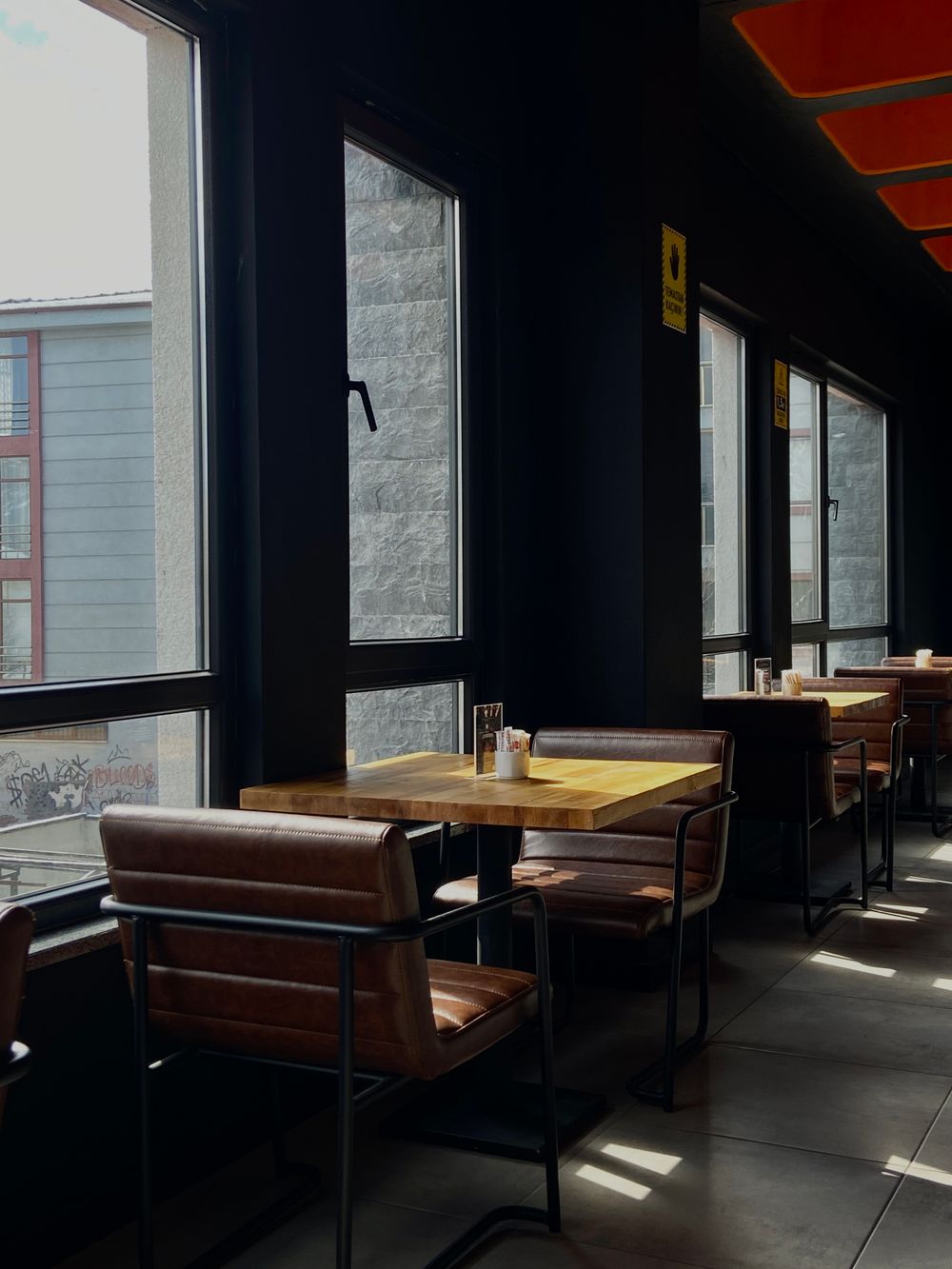 Cozy cafe interior with leather chairs and big windows at morning light