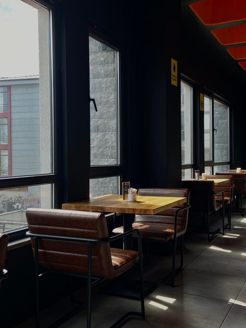 Free Bright cafe interior with sunlight streaming through large windows and modern decor. Stock Photo
