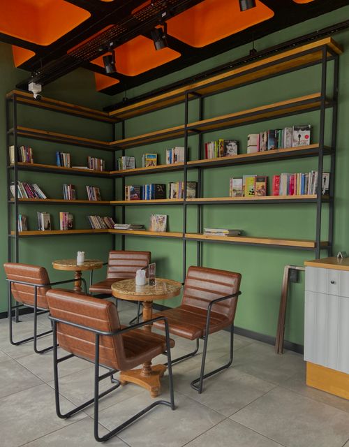 Free Charming reading corner with modern shelves, natural light, and leather seating for a relaxing ambiance. Stock Photo
