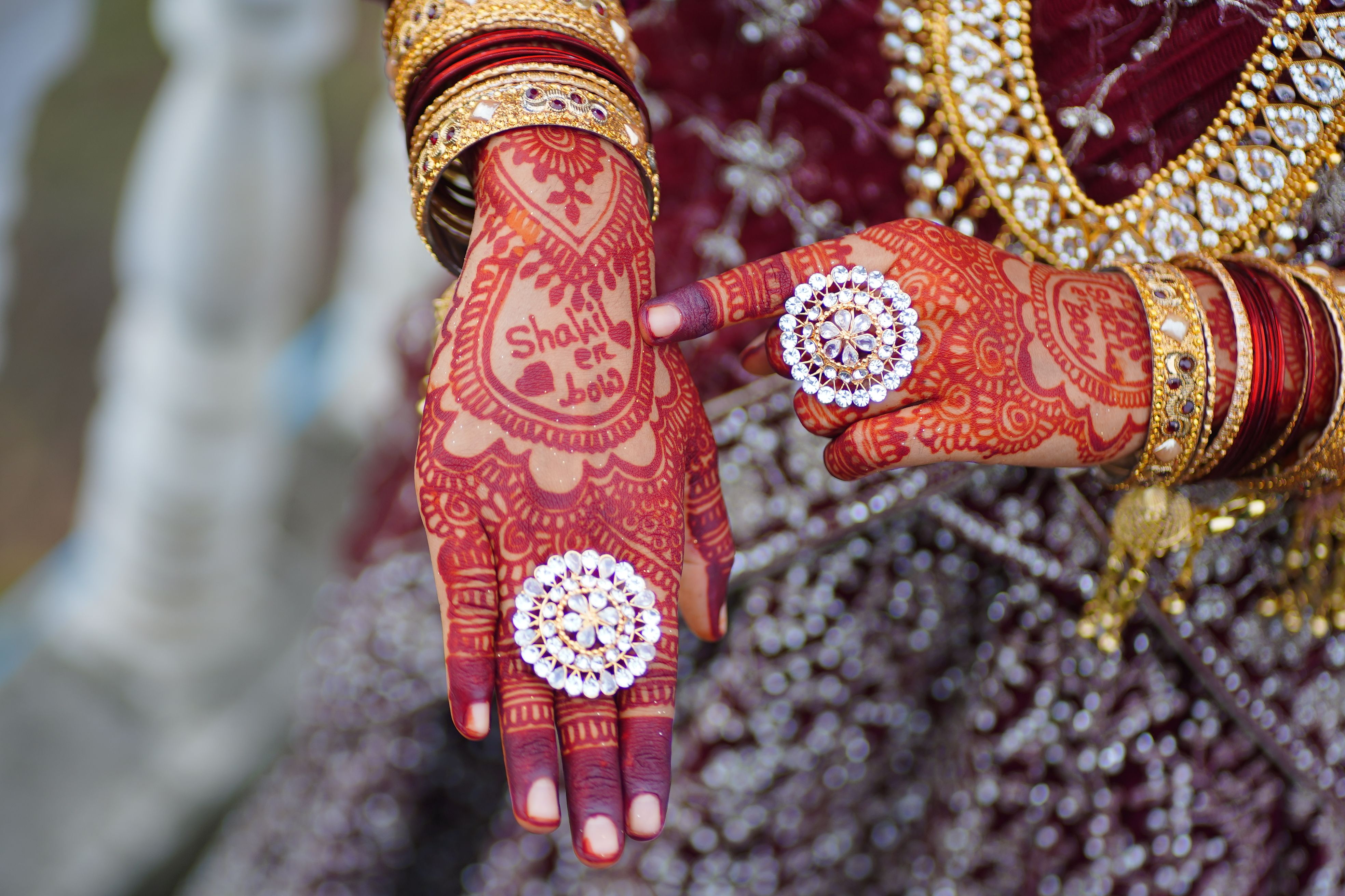 Close-up of bride's hands with mehndi and ornate jewelry, showcasing wedding elegance.