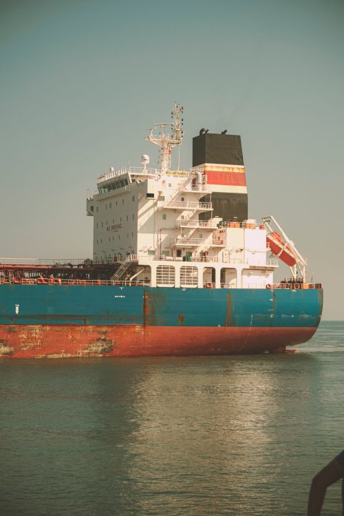 Free A large cargo ship on calm waters under a clear sky, captured during sunset. Stock Photo