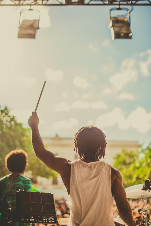 Back view Photo of Man Raising Drums Stick