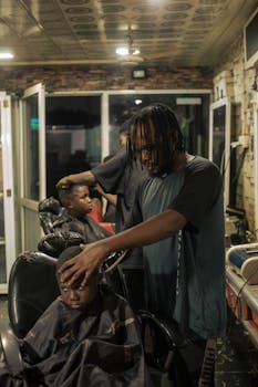 A focused barber trims a child's hair in a cozy, warmly lit barbershop