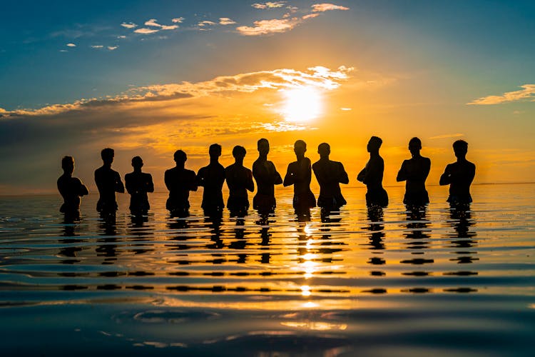 Silhouette Of People On Body Of Water