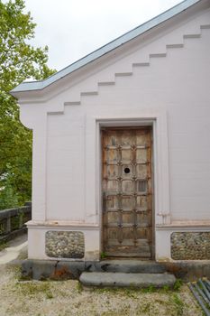 Close-up of a rustic wooden door set in a stone wall with geometric roof design.