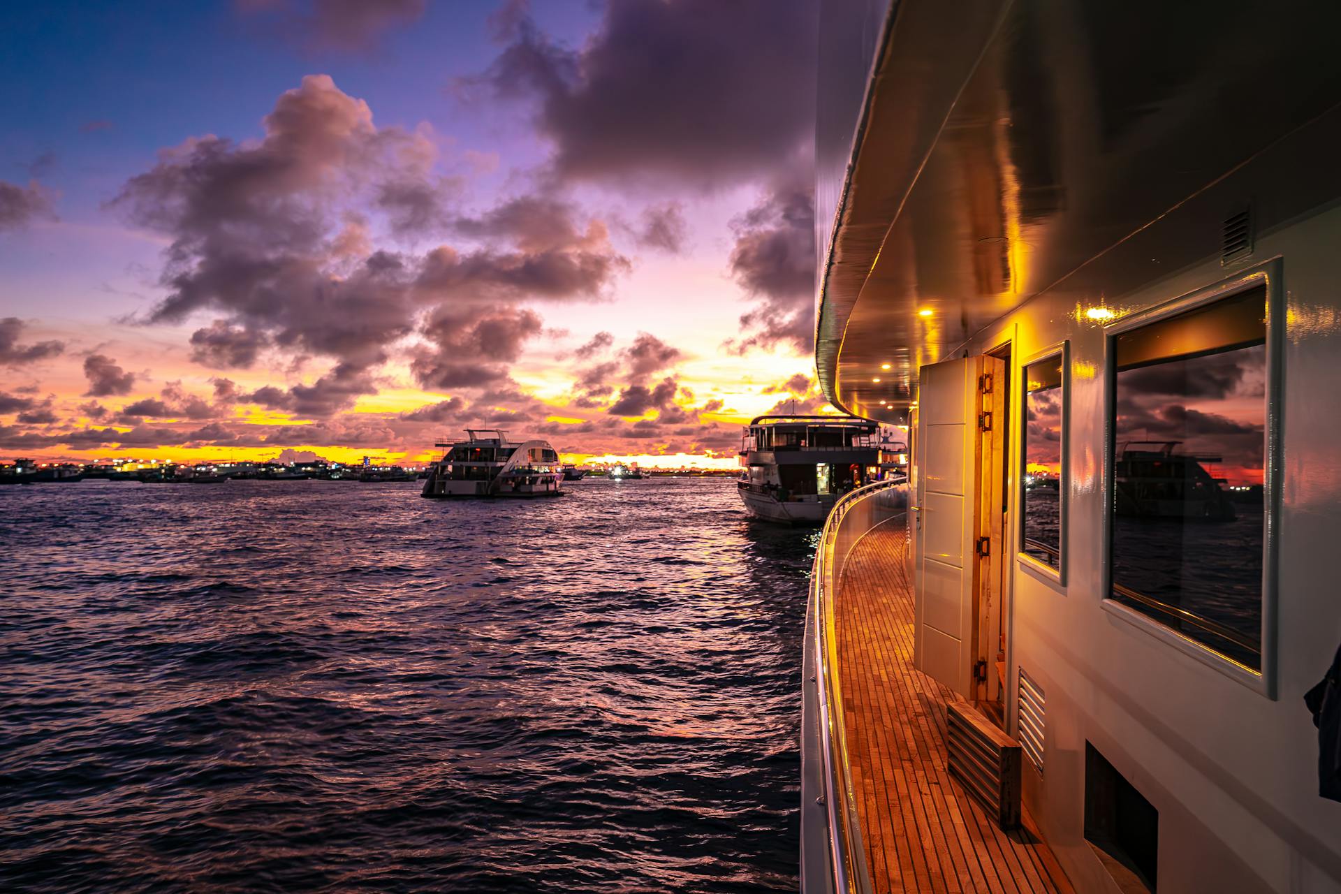 Stunning sunset over the Maldives with luxury yachts cruising the calm waters.